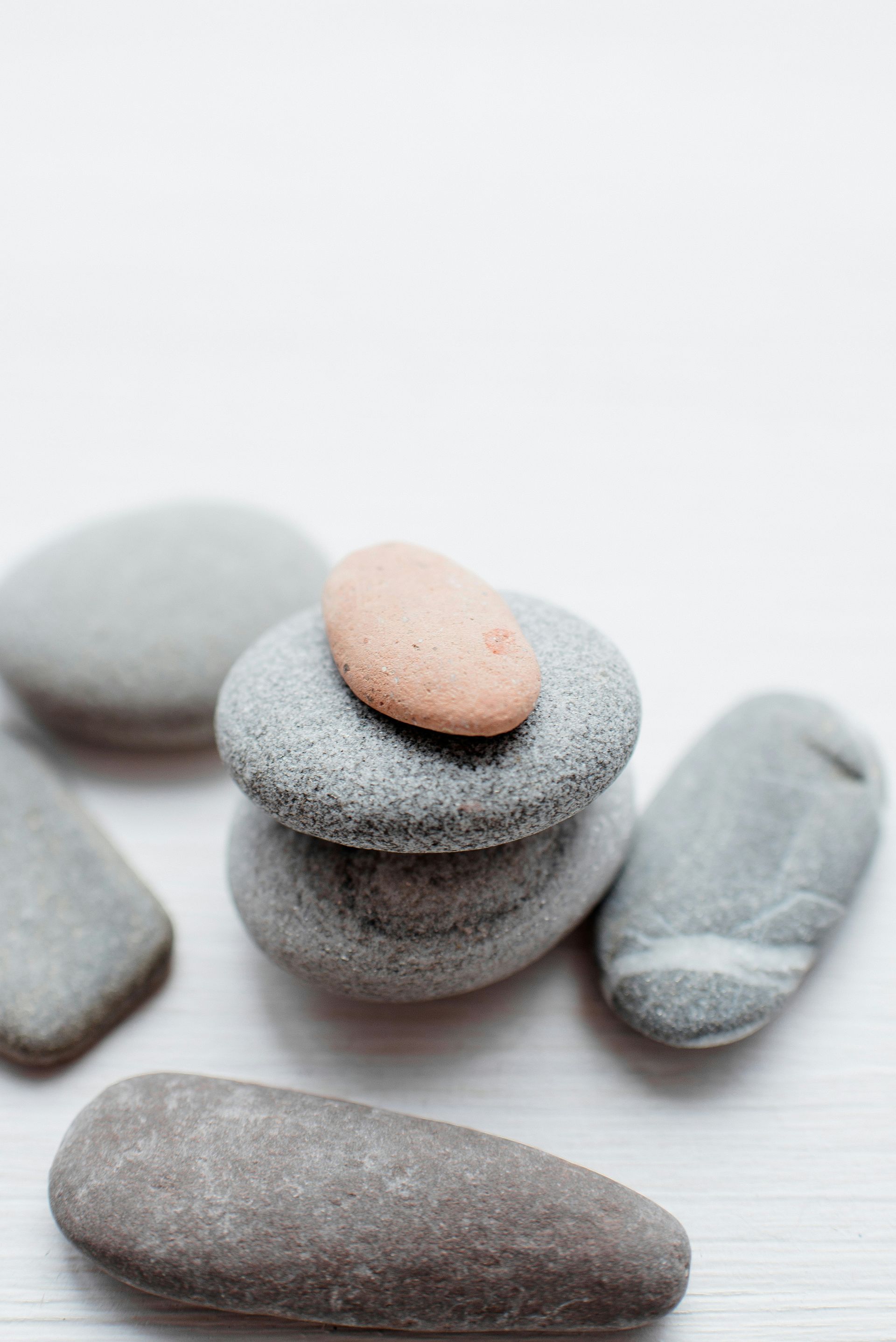 Smooth grey and pink stones stacked on a white surface.